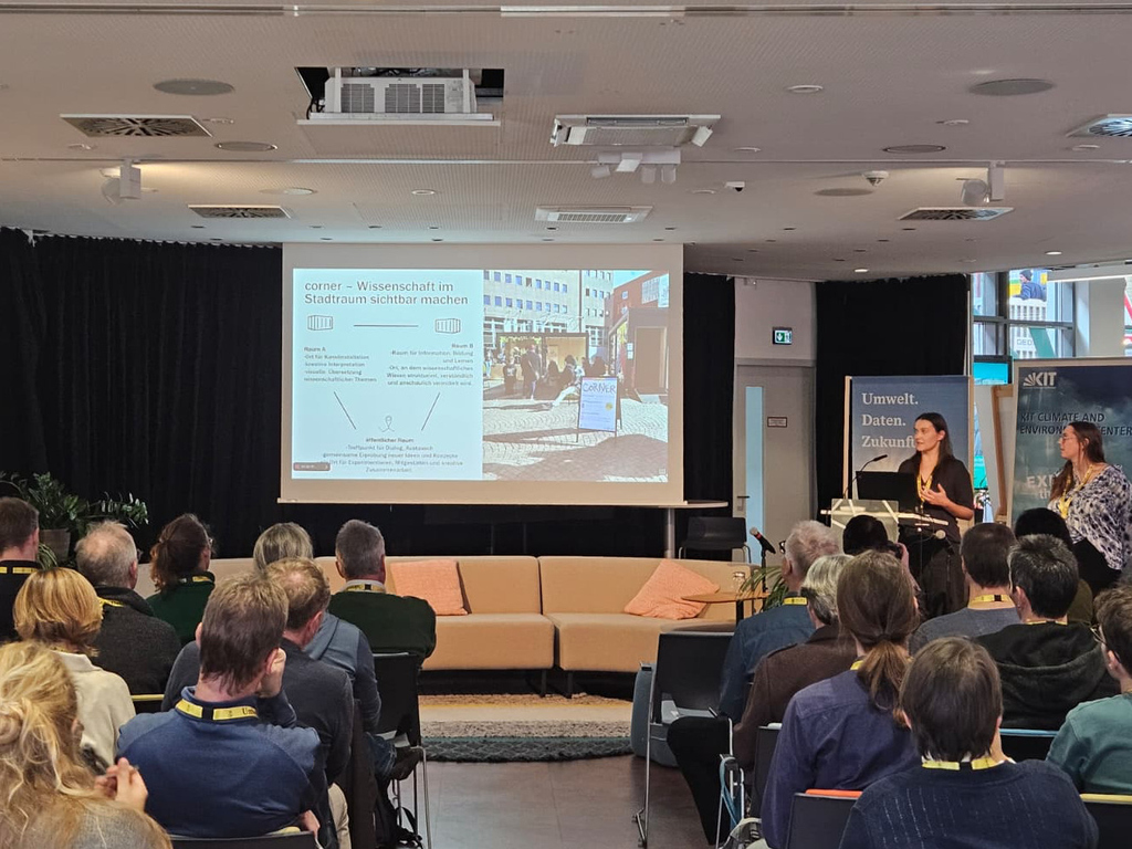 Vortrag über Wissenschaftskommunikation vor Publikum in einem Konferenzraum mit Präsentation.